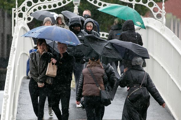 Members of the public brave the bad weather on the Hapenny Bridge in Dublin city centre